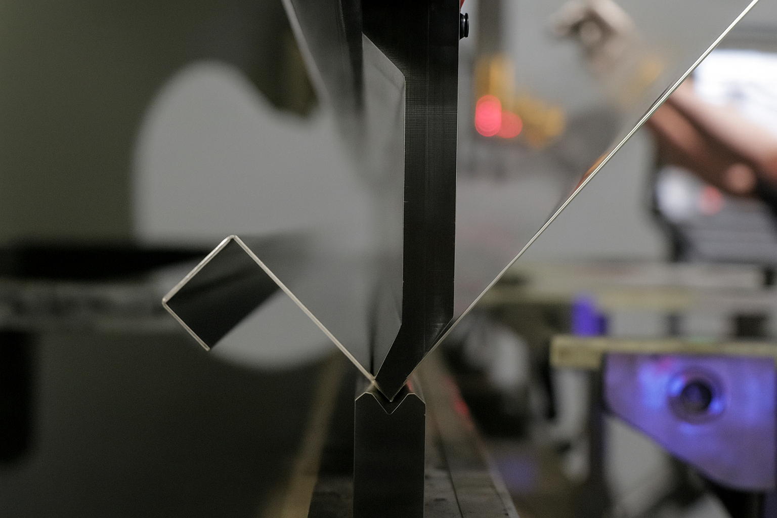 Industrial press brake forming a precise bend on sheet metal at Serpentix.